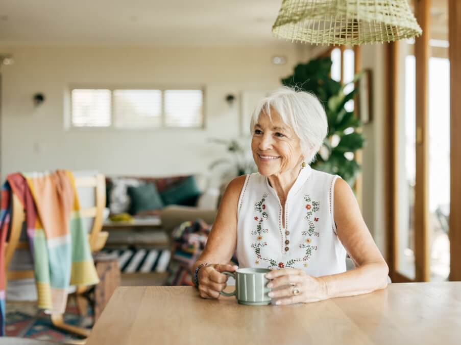 Senior woman sitting at a table with a mug