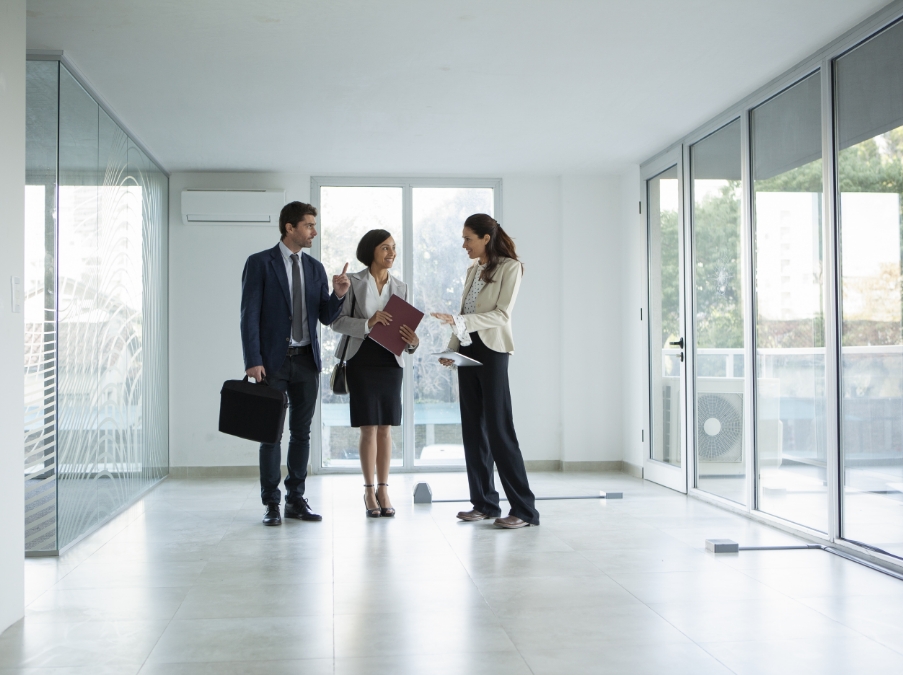 three people walking through a new building with large glass windows